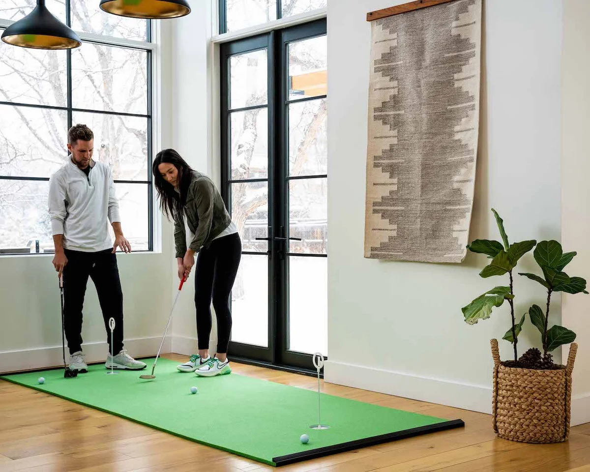 Couple using Birdieball putting green indoors
