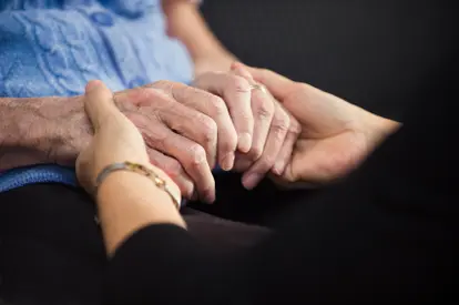 Home hospice worker holding a patient's hands