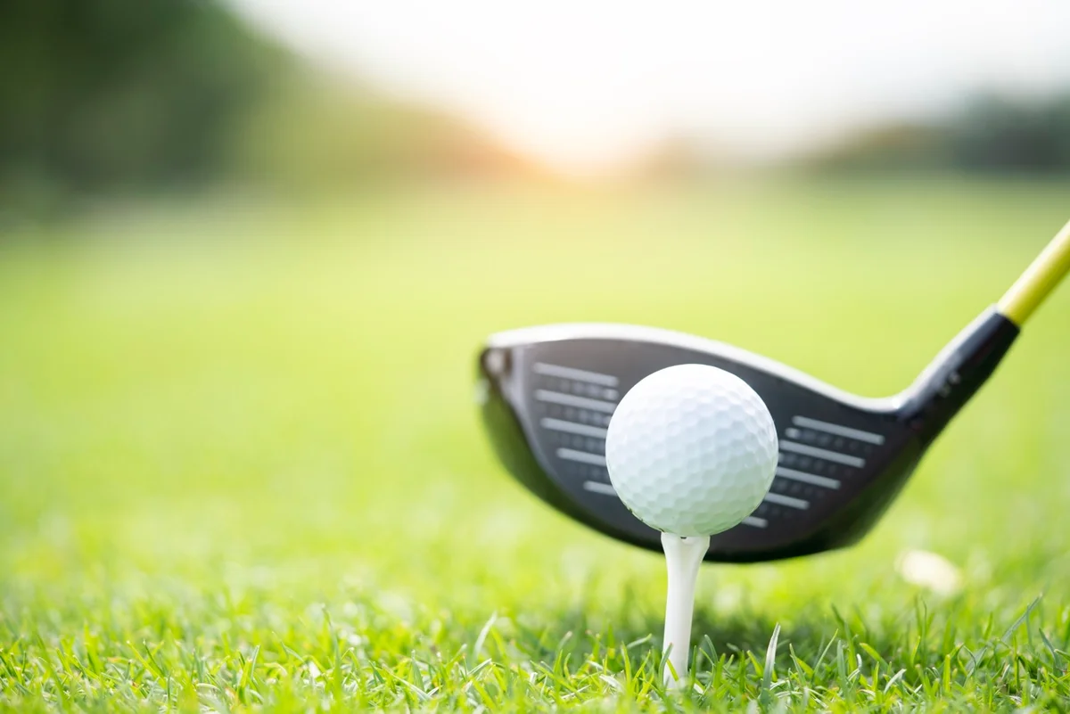 A driver hovers behind a teed up ball