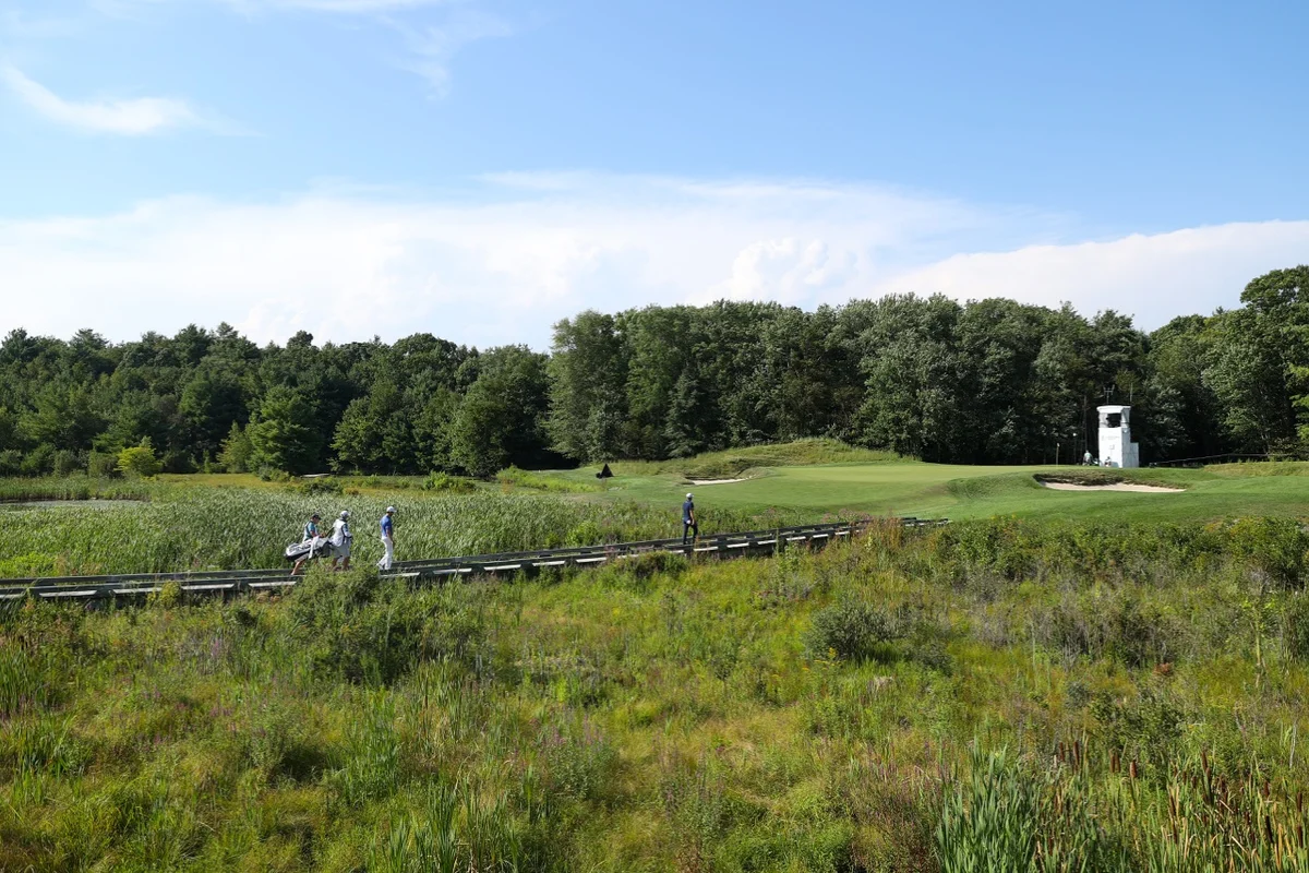 Golfers cross a bridge at TPC Boston