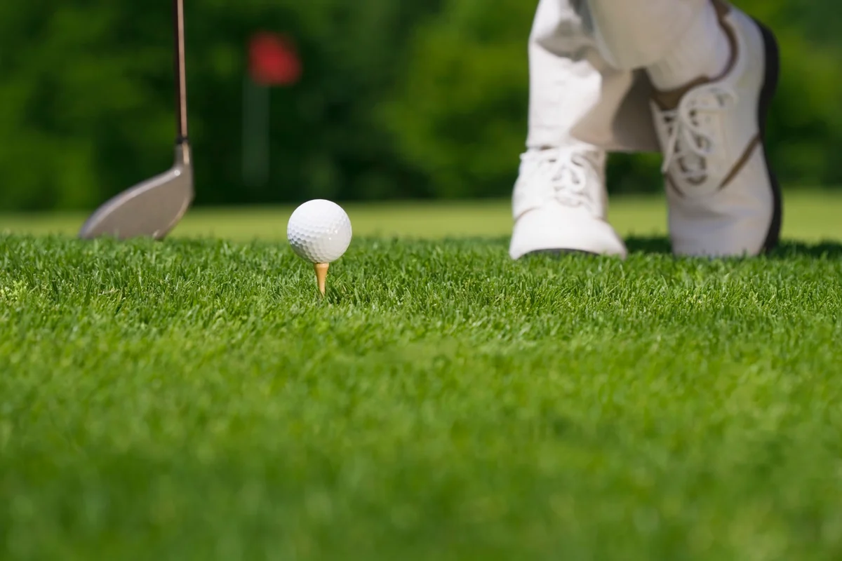 Golfer waits on tee with feet crossed