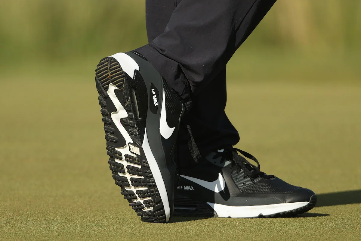 black Nike golf shoes on green