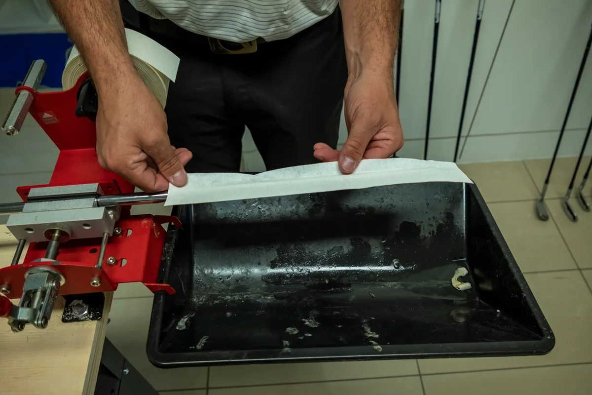 golfer applies new grip tape to shaft