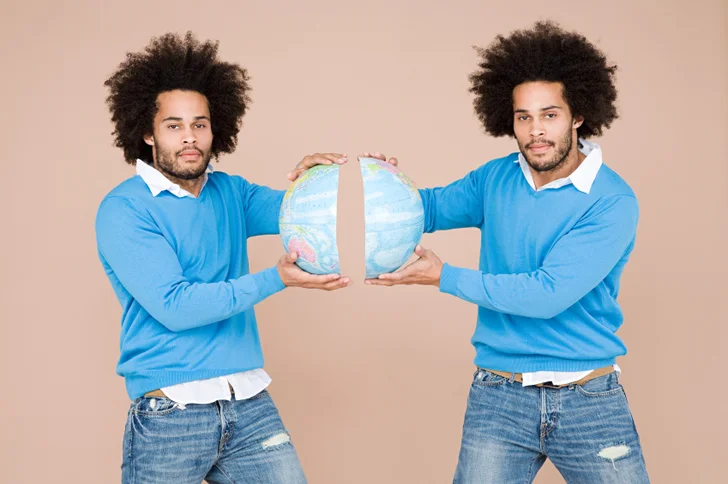 twins holding apart a globe
