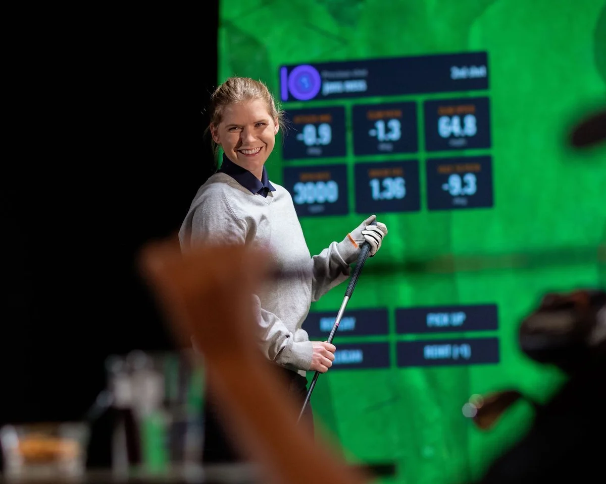 woman smiling with TrackMan Golf simulator