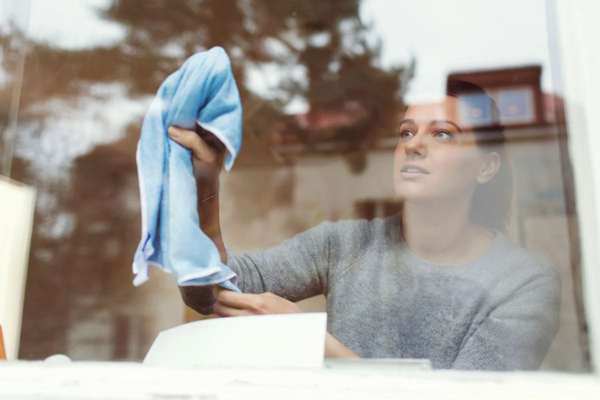 Woman cleaning glass of window
