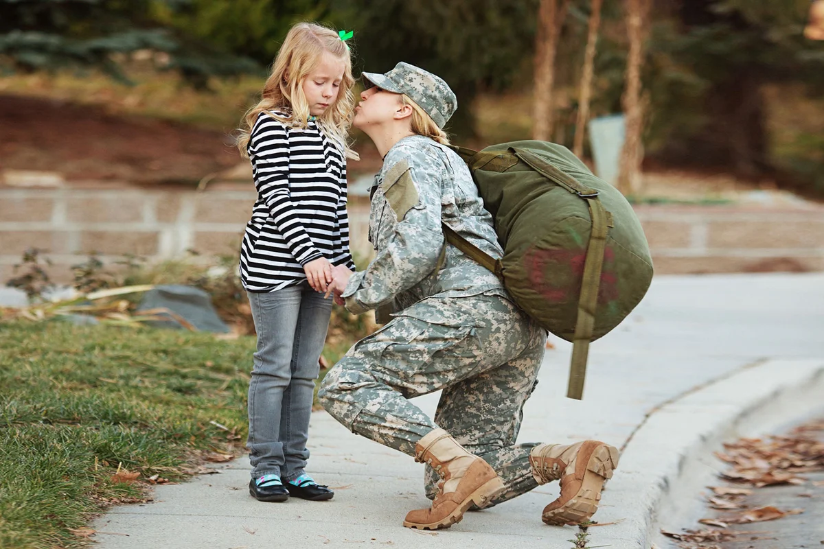 Military mother kissing her daughter goodbye