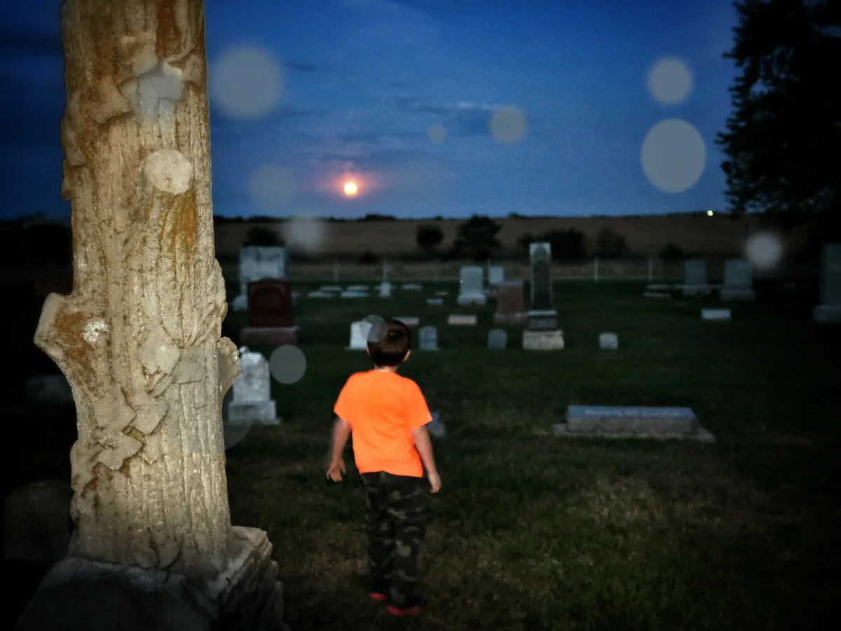 boy at cemetary with orbs