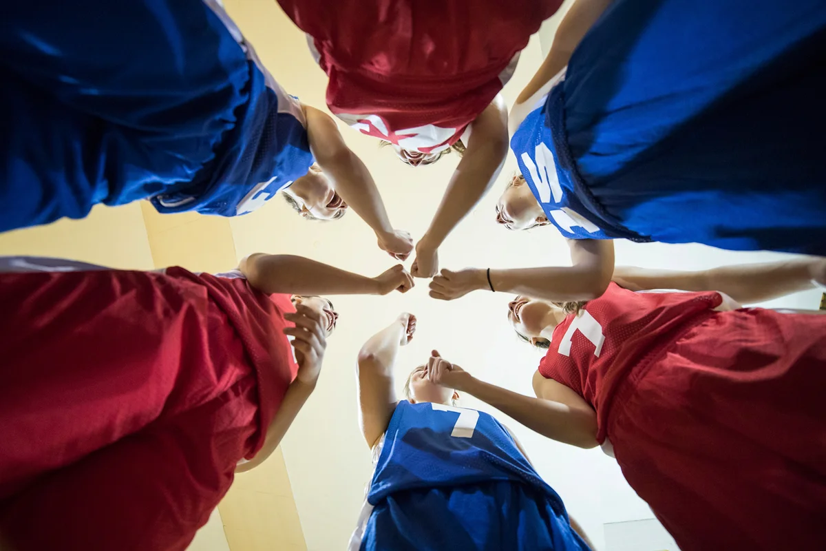 Teenage girl athletes cheering after their team huddle