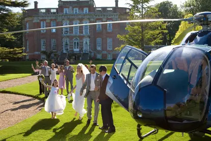 Wedding guests waving at bride and groom by helicopter
