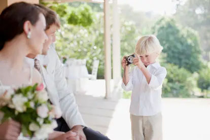 Boy taking picture bride and groom