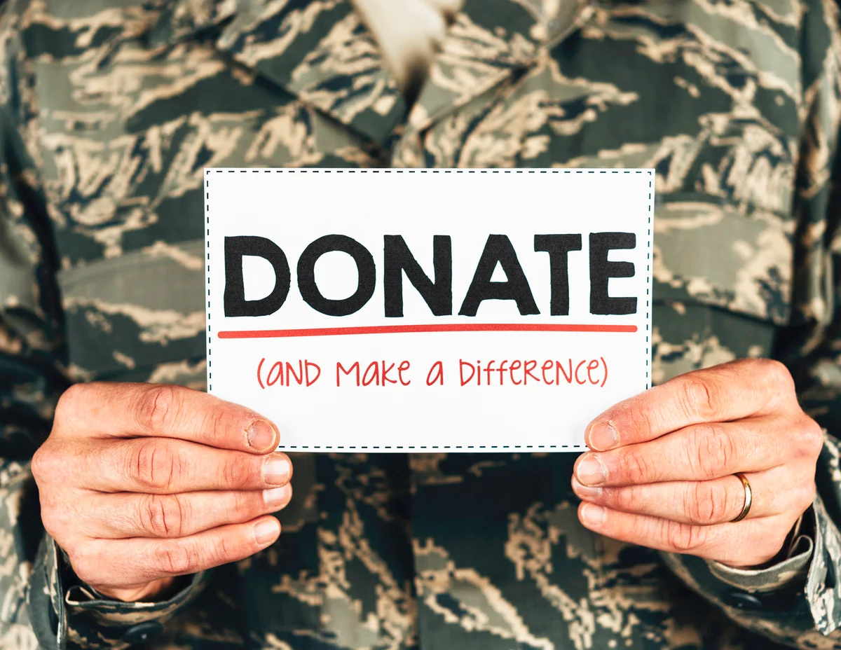Military service member with donate sign