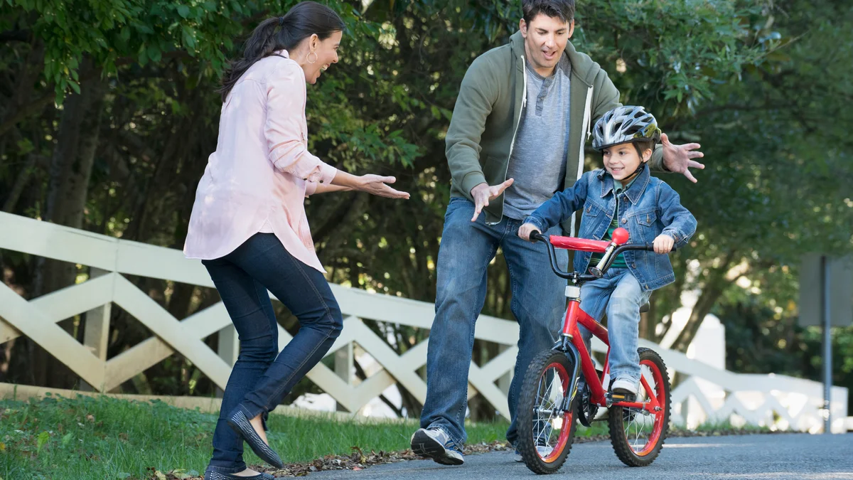 parents helping son riding bicycle