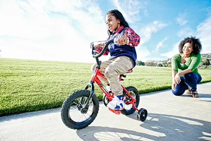 mother watching daughter riding bicycle