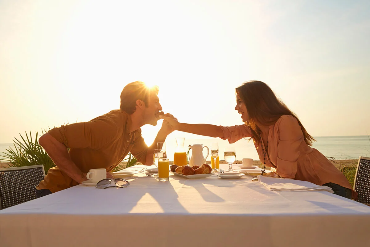 Woman feeding man at sunset dinner outdoors