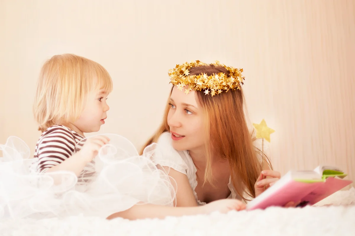 Mother and cute little girl reading in bed
