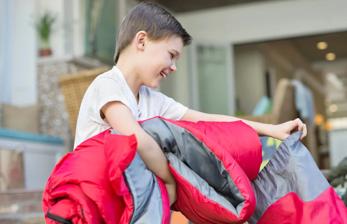 boy packing rolled up sleeping bag