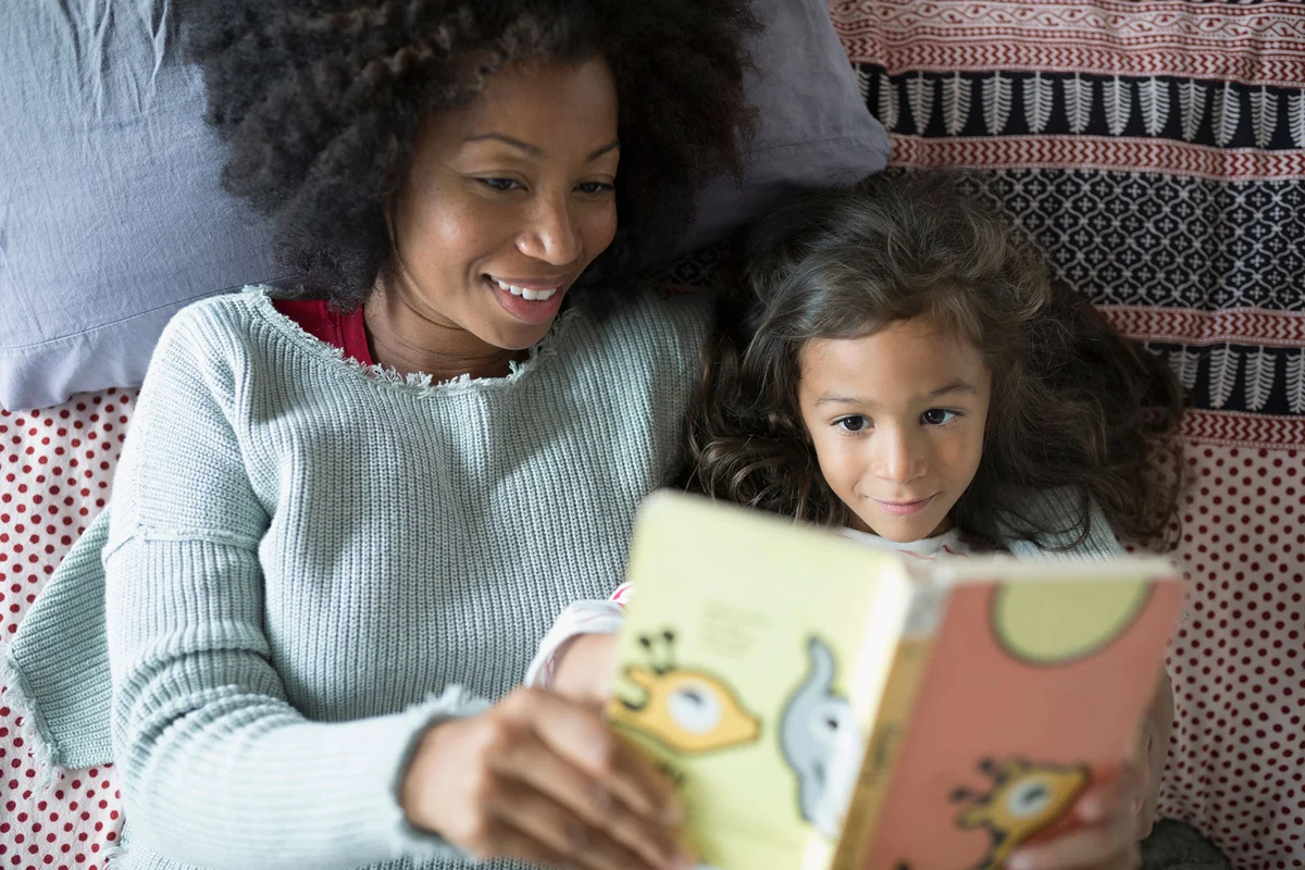 Mother and daughter reading book in bed