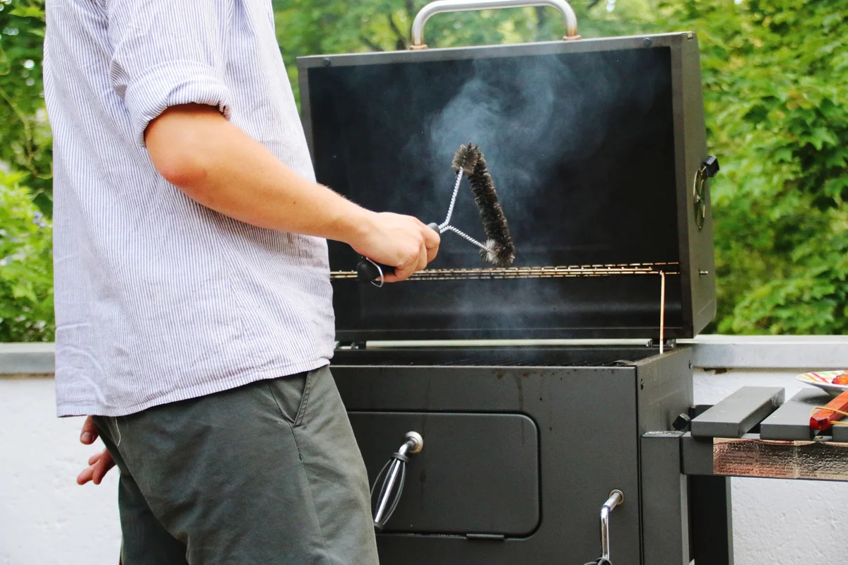 Man Cleaning Barbecue Grill With Wire Brush