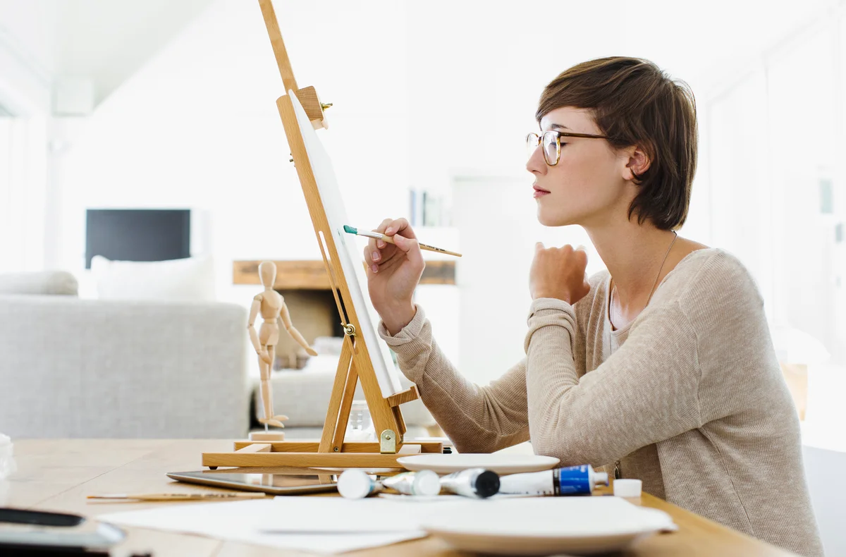 Woman painting on easel at table