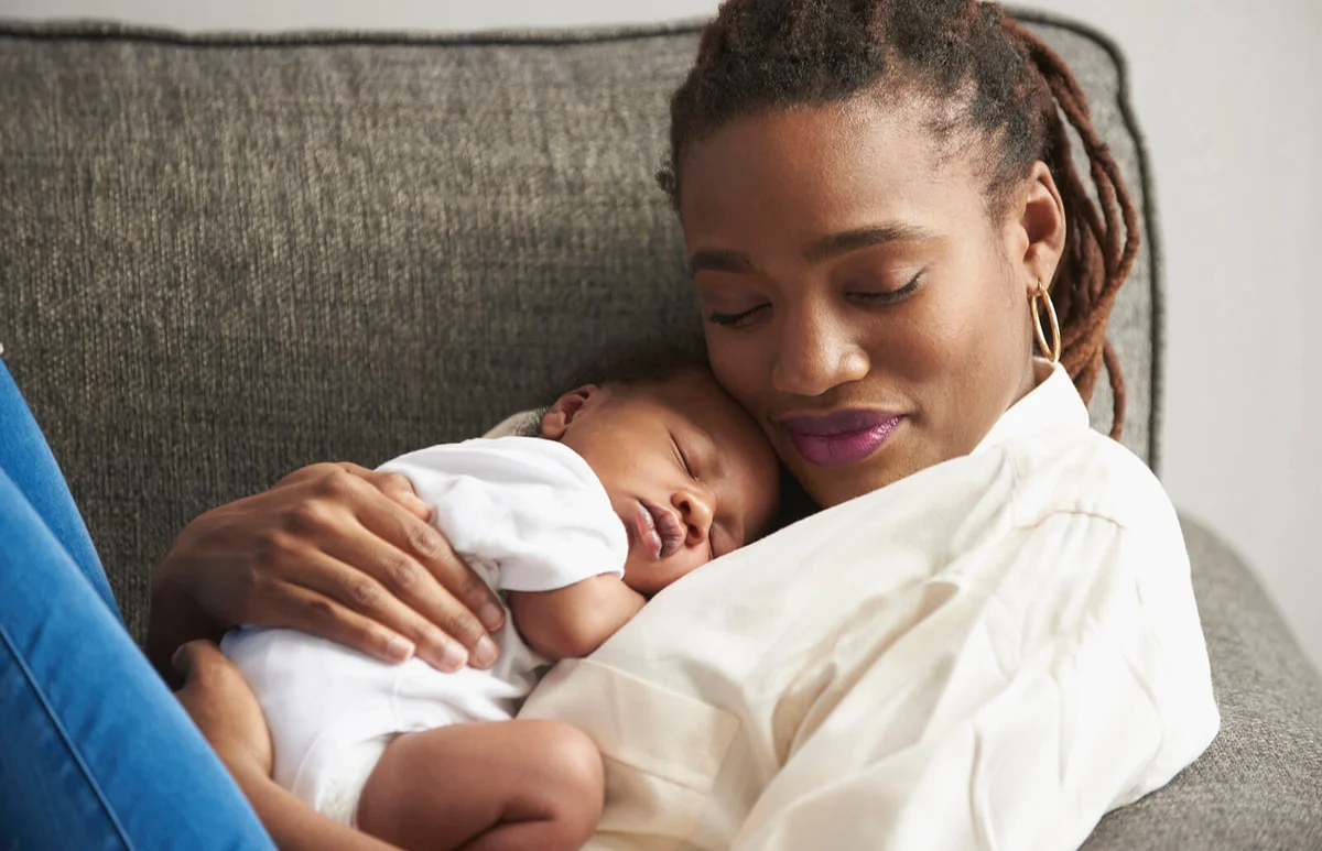 mother cuddling sleeping baby son on sofa