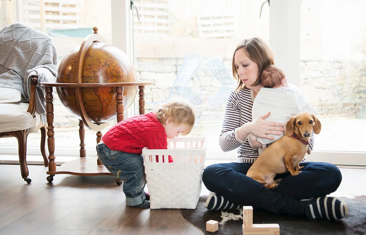 Boy playing at home with mother and baby sister