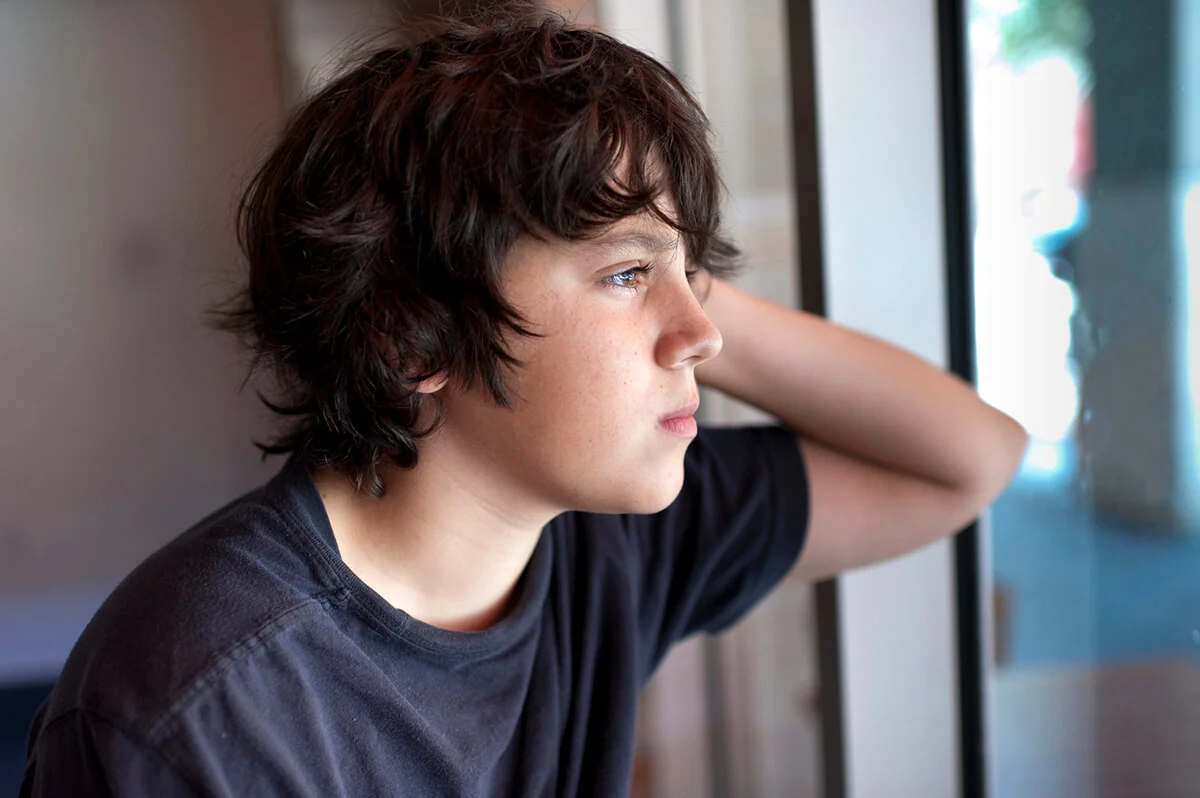 Pensive child looking through a window