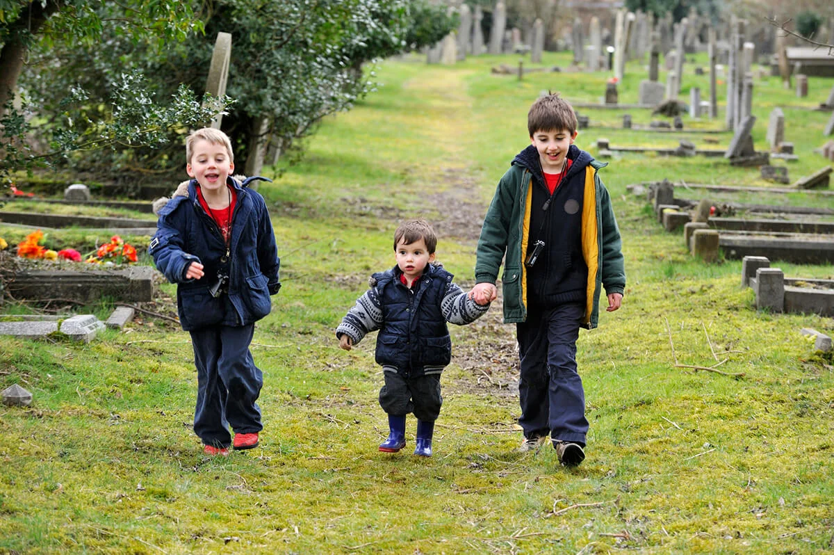 Three young brothers walking in a cemetery