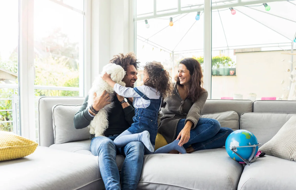 Happy family with dog sitting together in cozy living room