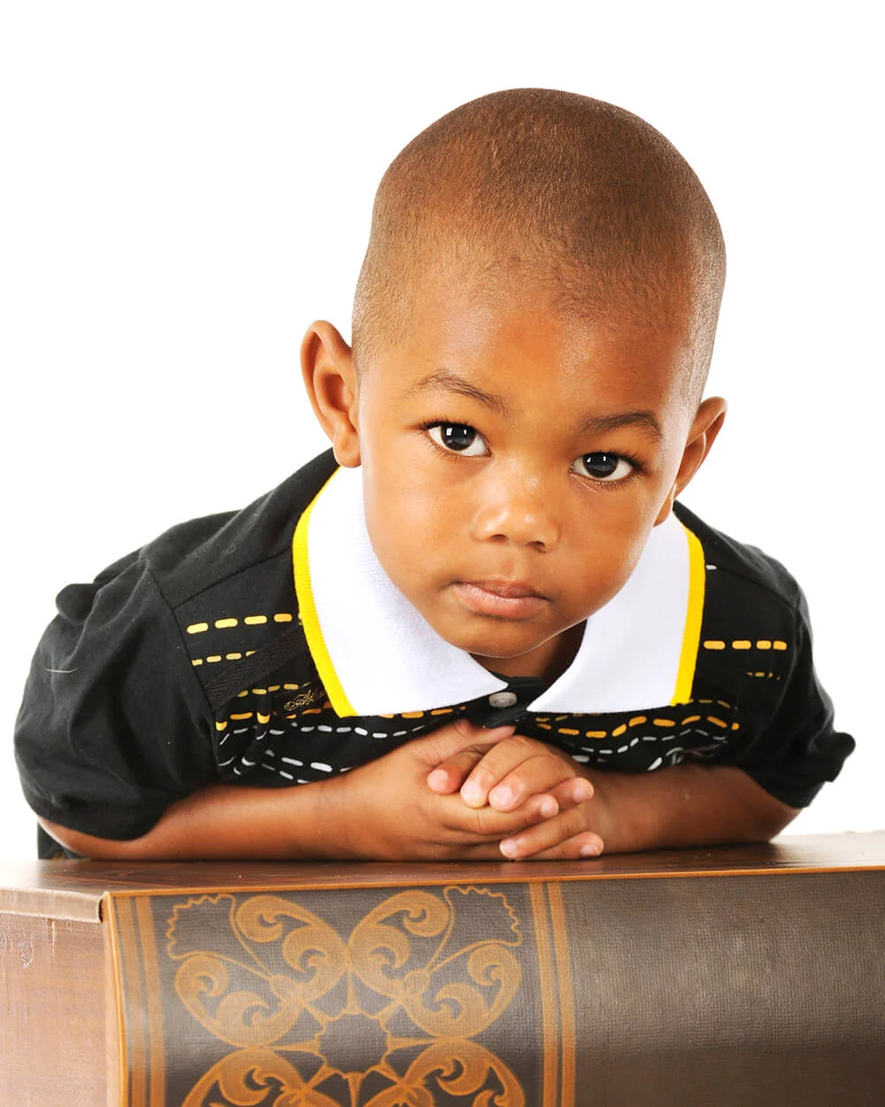 adorable preschooler looking at the viewer while leaning over a huge book