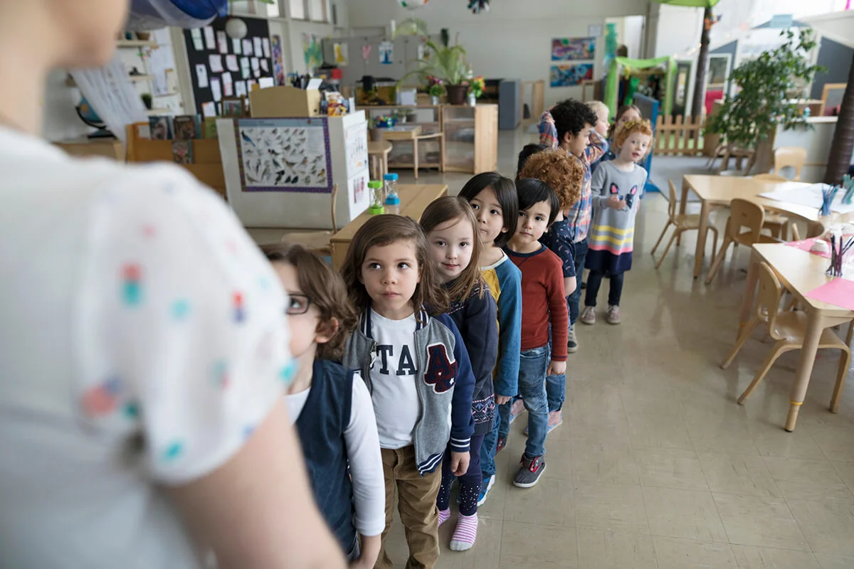 Preschool students lining up for teacher in classroom