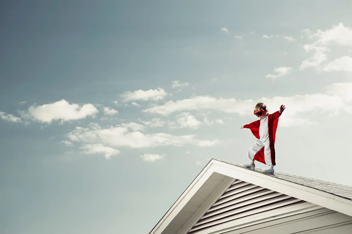Boy in cape at edge of roof