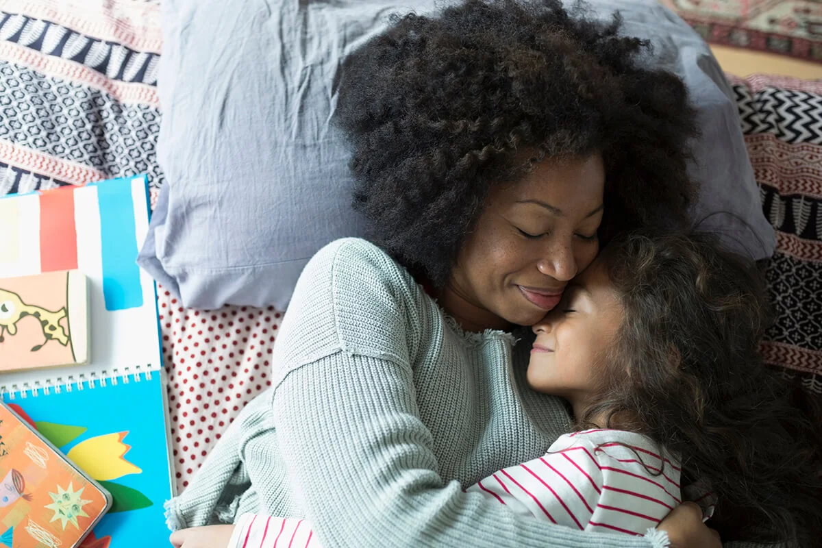 smiling mother and daughter hugging on bed
