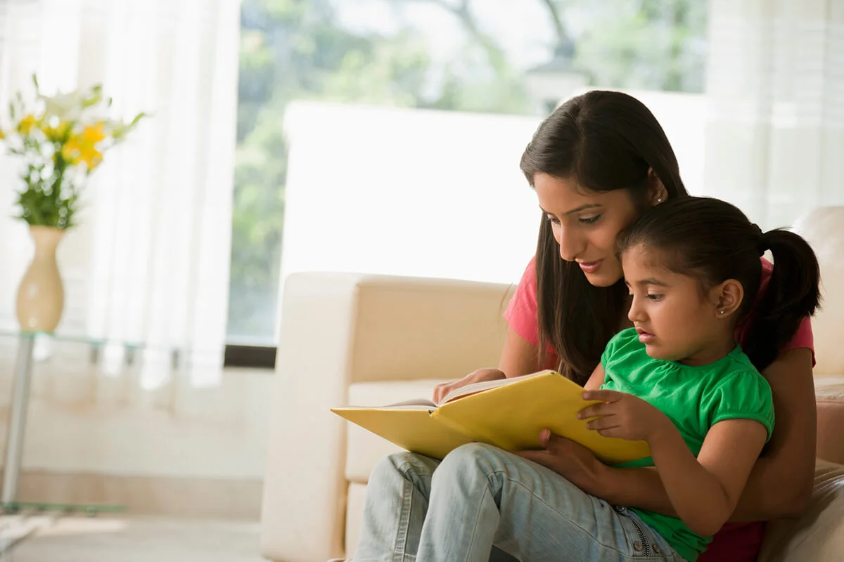 Mother reading book with daughter
