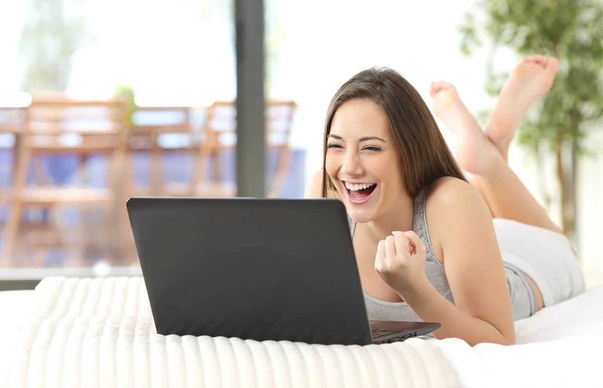 Excited woman winning online watching laptop