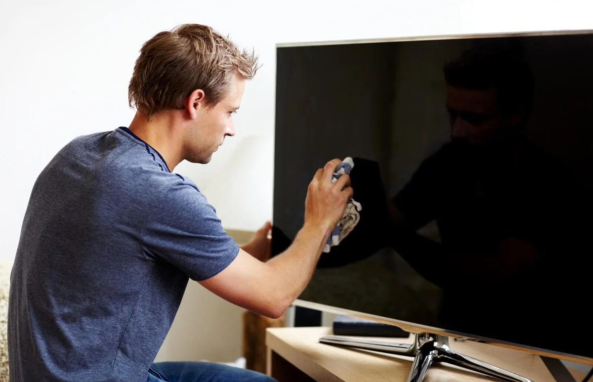 Man cleaning the screen of his smart TV