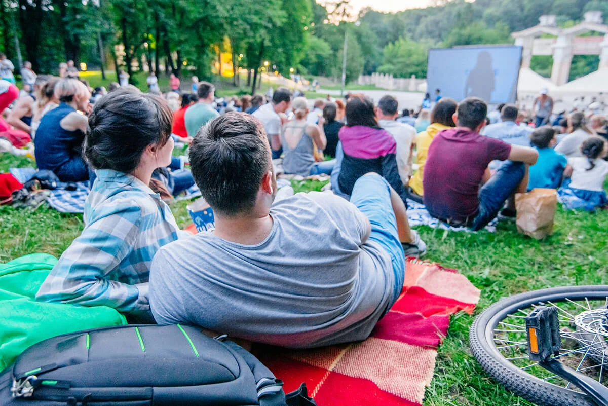 Couple watching movie in open air cinema in city park