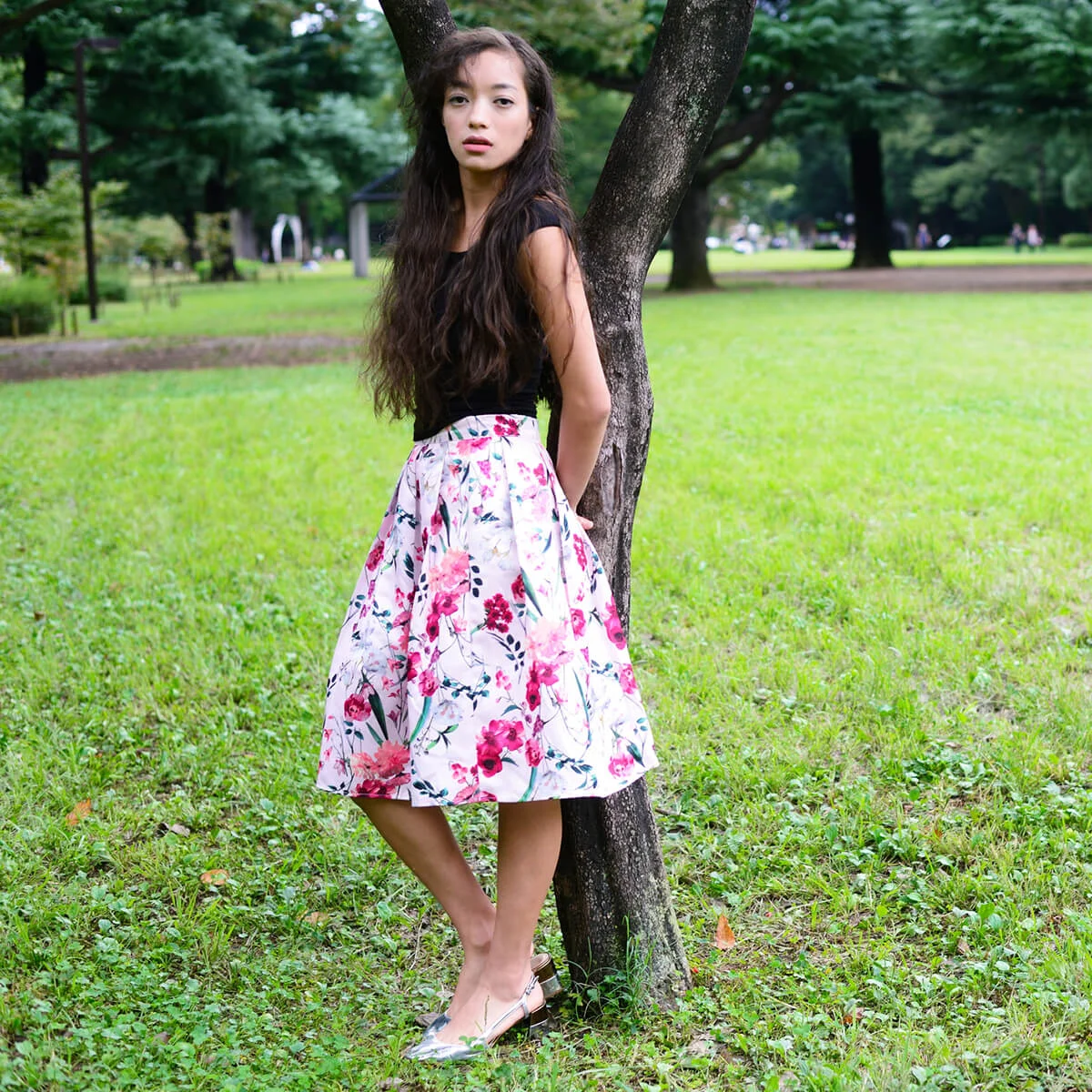 A young woman leaning against a tree at sunset