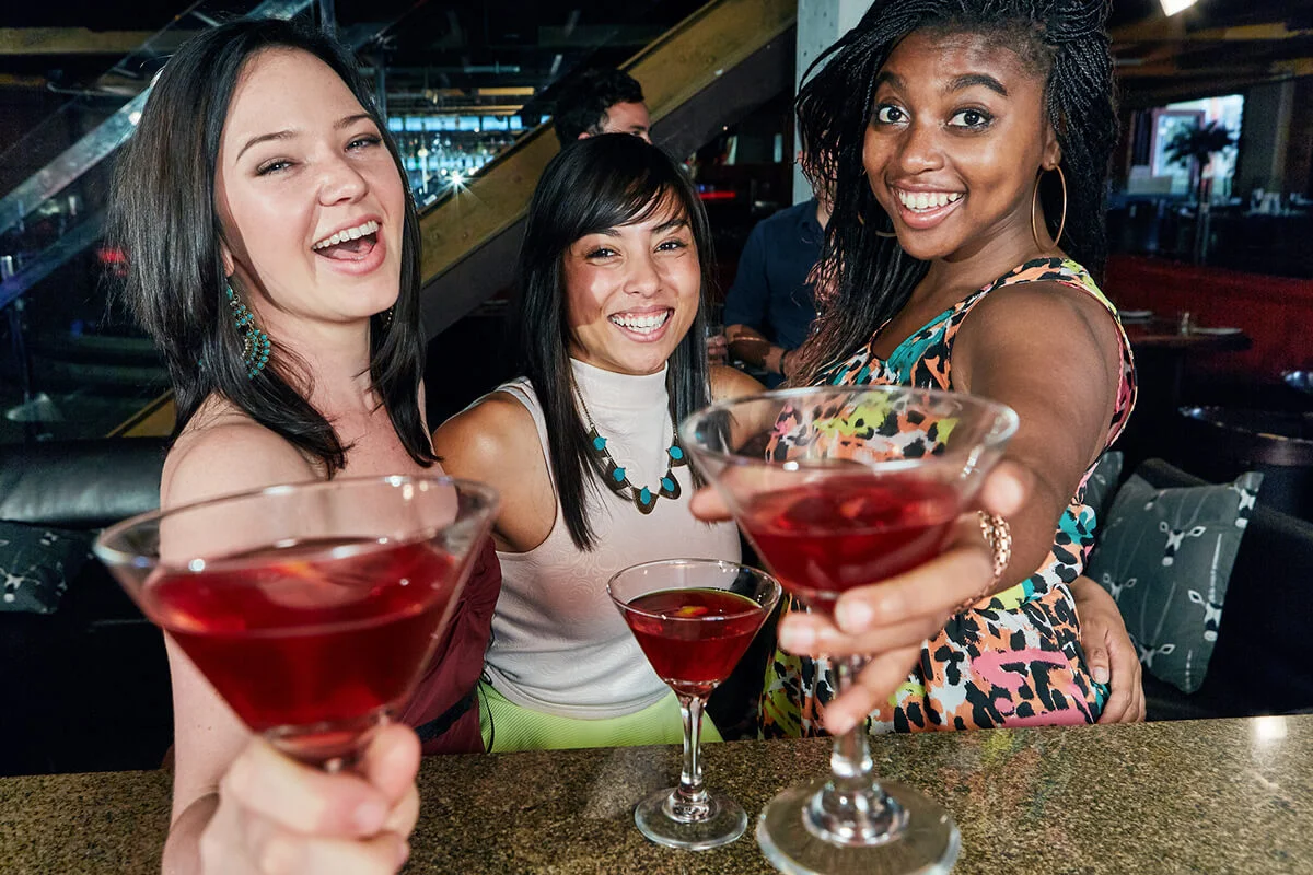 Three happy young women toasting in cocktails