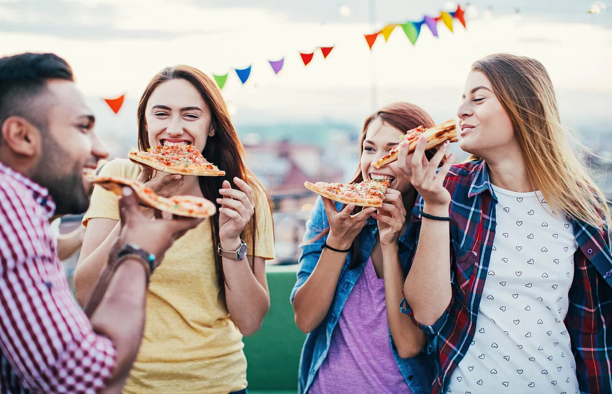 Young people eating pizza on a rooftop party