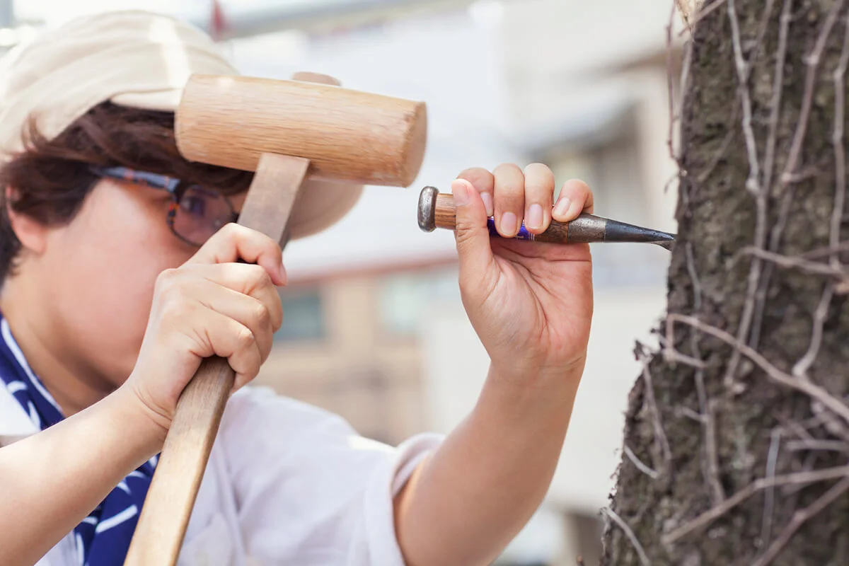 woman sculptor while carving buddha face on a tree