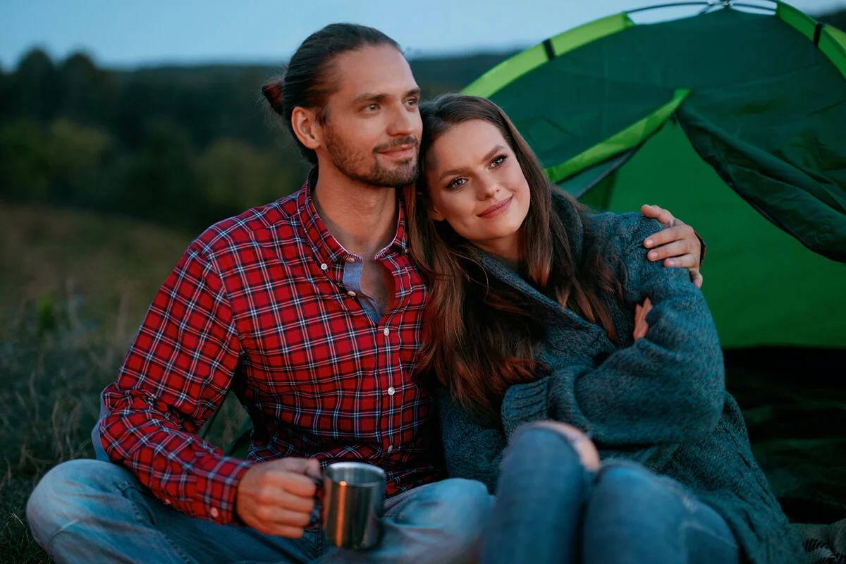 Couple Near Camp Drinking Hot Drinks And Enjoying Travel On Weekend
