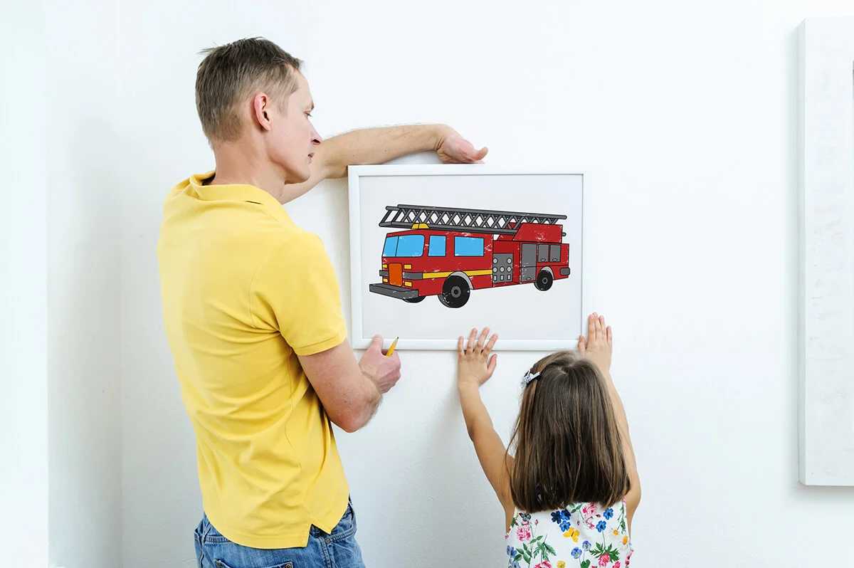 Father and daughter are hanging the picture