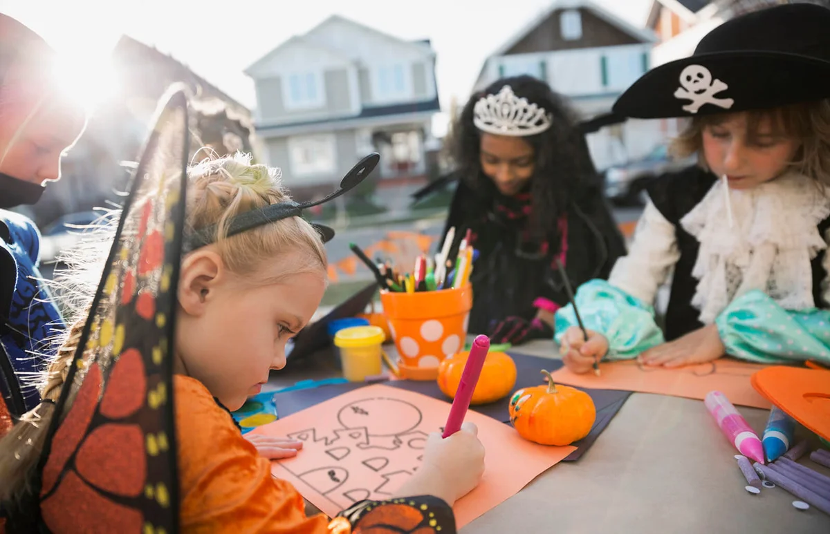 Kids in Halloween costumes doing crafts front yard