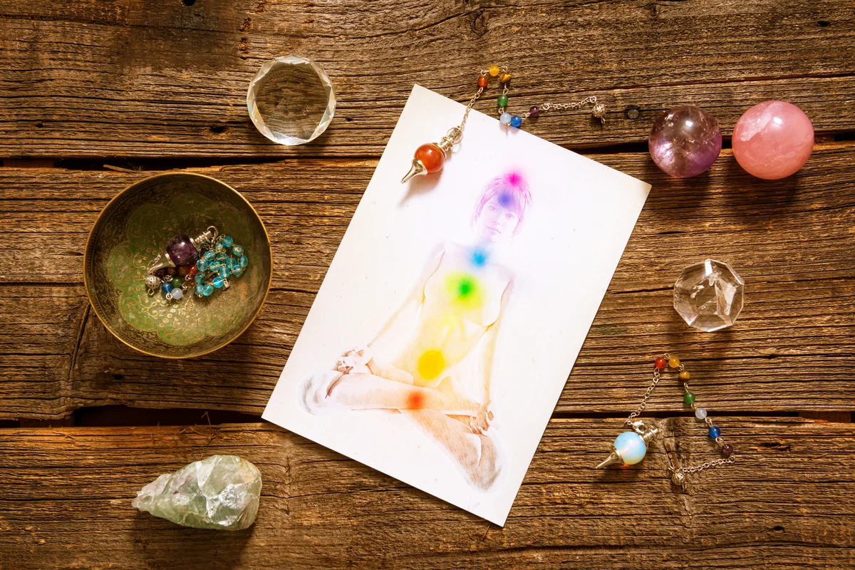 Chakras illustrated over human body with natural crystals and pendulum
