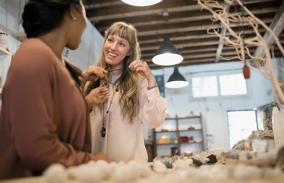 Women friends shopping browsing necklaces in new age shop