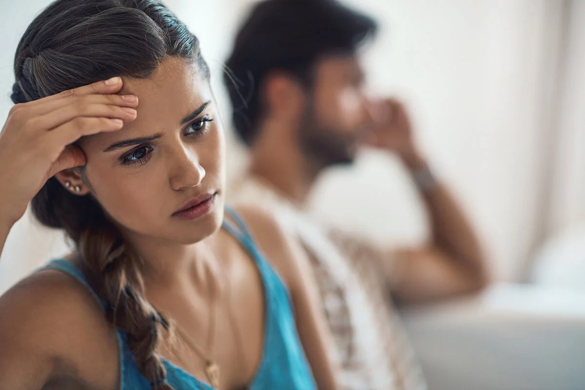 couple having an argument while sitting on their couch at home