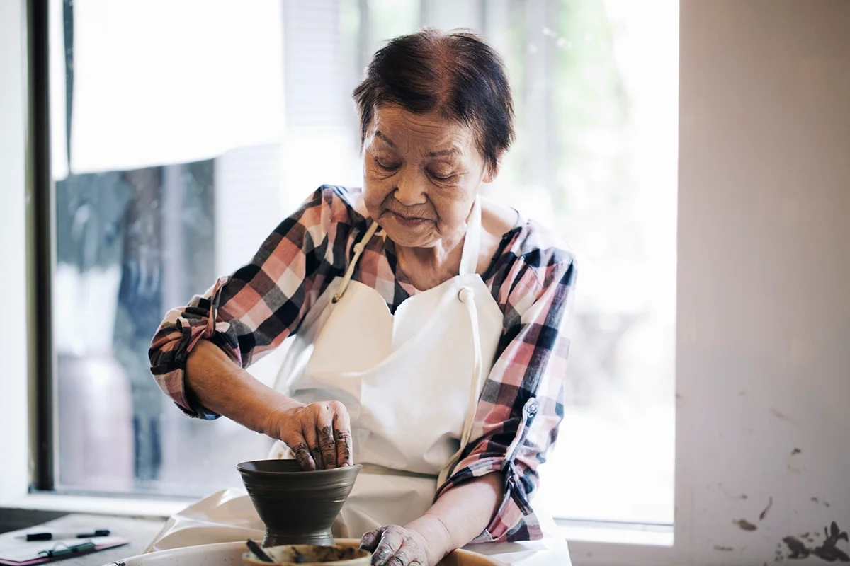 Senior woman making ceramic work with potter's wheel