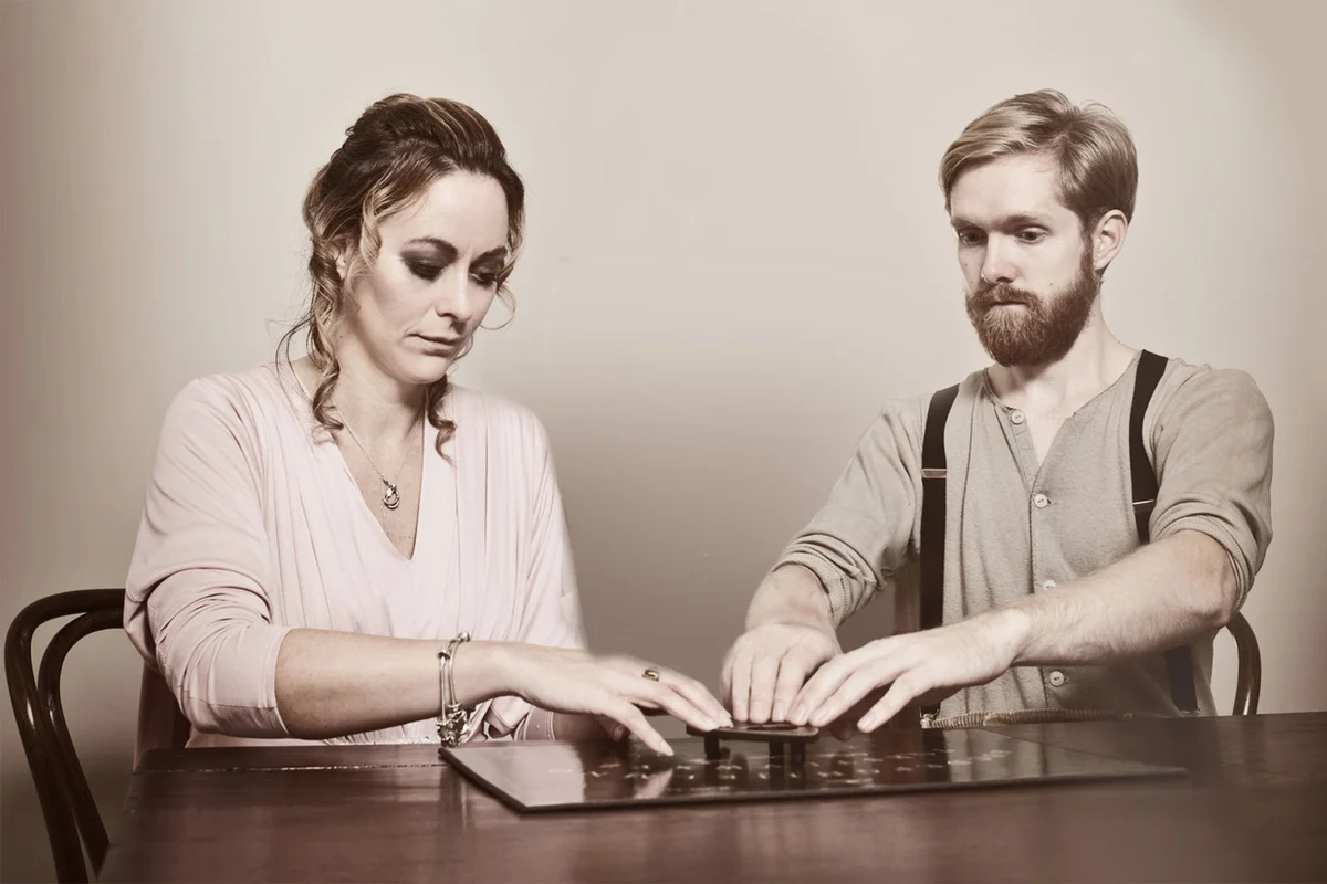 Man and woman using Ouija board
