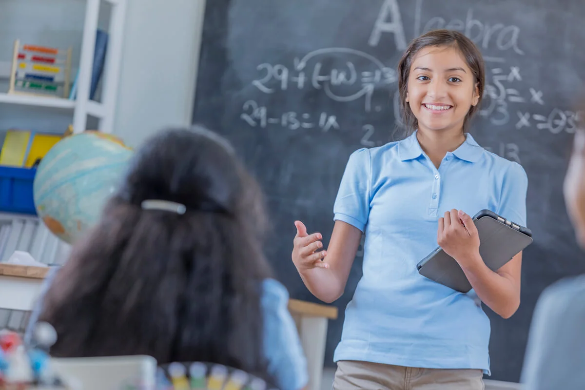 junior high schoolgirl holds a tablet while giving a speech